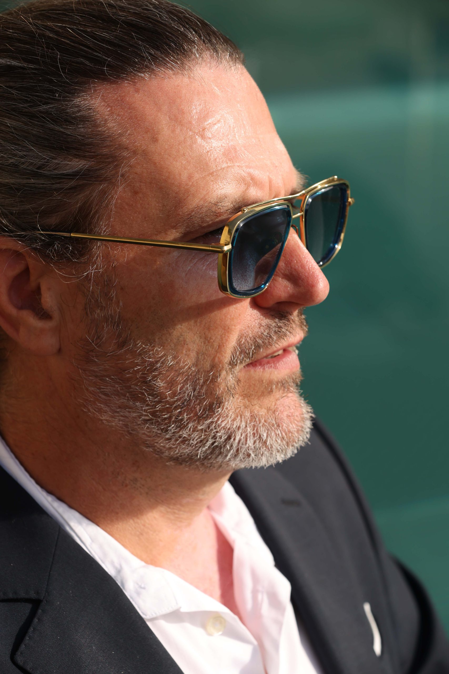 Forja Halo block titanium sunglasses in 18K gold with blue acetate ring, worn in profile